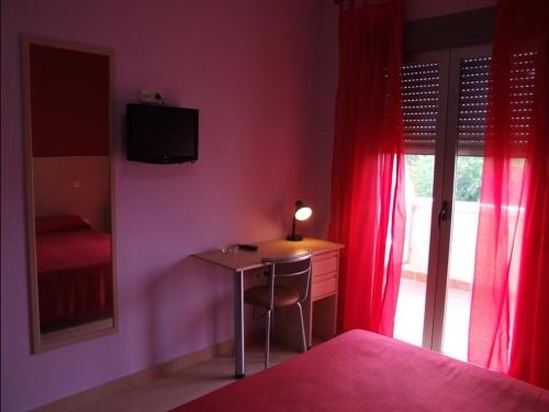 1 dormitorio con escritorio, lámpara y ventana en Hostal Parador de los Galanes, en Manzanares