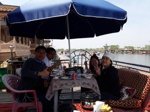 a group of people sitting at a table under an umbrella at Lake Palace Group Of House Boats in Srinagar