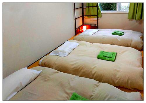 Tres camas en una habitación con toallas verdes. en Casa Sanpond, en Kanazawa