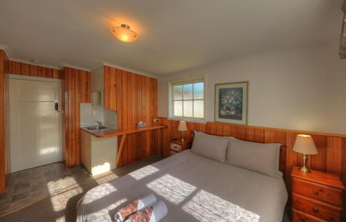 1 dormitorio con 1 cama grande y TV en Grace's Spa Cottage, en Smithton