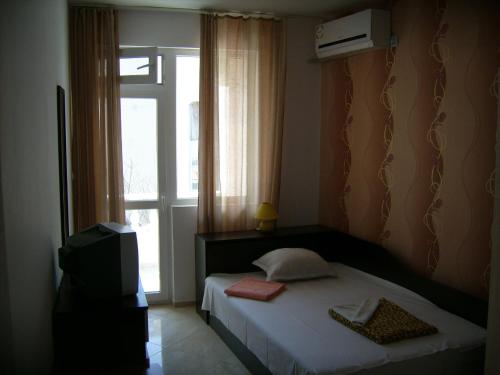 a bedroom with a bed with a window and a television at Hotel Pasians in Pomorie