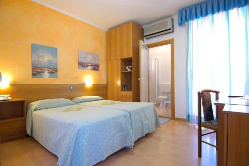 una camera d'albergo con letto, scrivania e finestra di Hotel Ai Pini a Grado