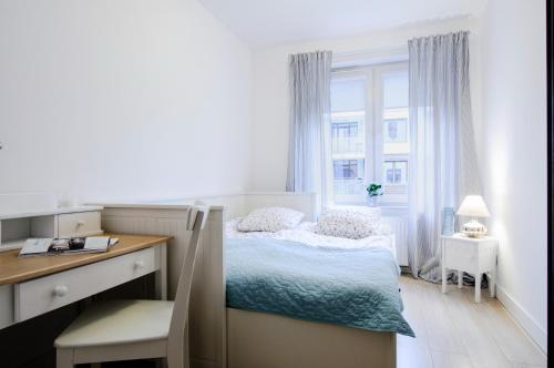 Schlafzimmer mit einem Bett, einem Schreibtisch und einem Fenster in der Unterkunft Apartament z basenem Polanki in Kołobrzeg