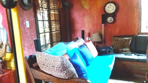 a living room with a blue couch and a clock at Vila Santa Rosa Guest House in Ilhabela