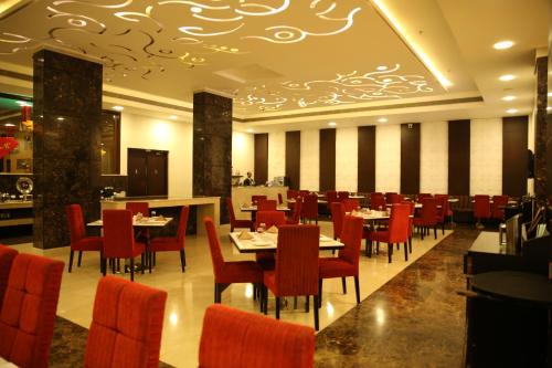 a dining room with tables and red chairs at Ramada Jamshedpur Bistupur in Jamshedpur