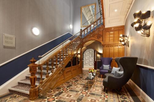 a lobby with a staircase with a chair and a stair case at Oddfellows On The Park in Cheadle