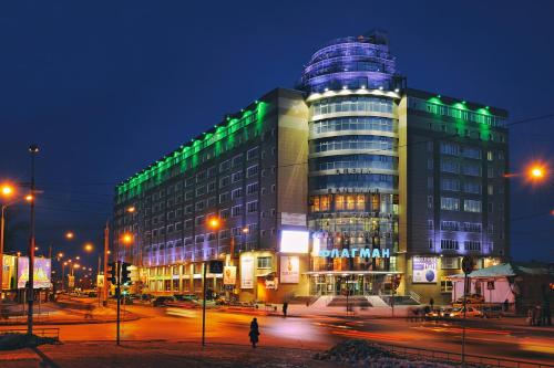 a building with green lights on a city street at night at Flagman in Omsk