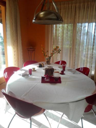 a table with a white table cloth and red chairs at B&B Villa Claudia in Lavena Ponte Tresa