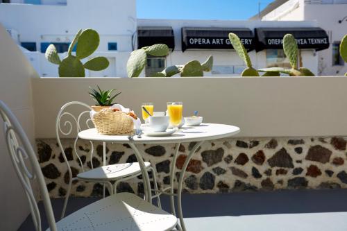 a table with two chairs and two glasses of orange juice at Fileria Suites in Oia