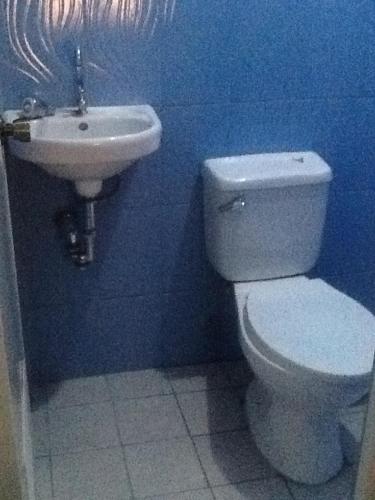 a blue bathroom with a toilet and a sink at Angeles City Guesthouse in Angeles