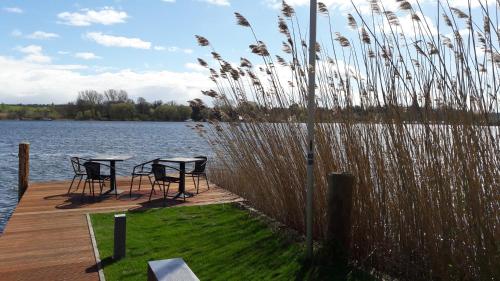 two tables and chairs on a dock next to a lake at Hotel Villa Passion in Malchow