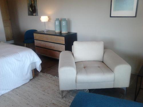 a bedroom with a white chair and a bed at La Maison de Charlie in Vaugines