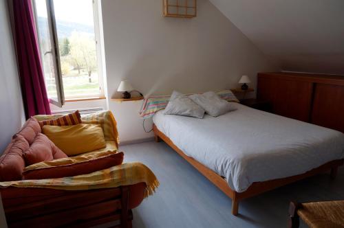 ein Schlafzimmer mit einem Bett, einem Stuhl und einem Fenster in der Unterkunft Gite tout confort in Jausiers