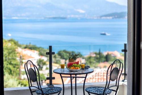 einen Tisch mit einer Schale Obst und Getränken auf dem Balkon in der Unterkunft White Olive Villa in Herceg-Novi