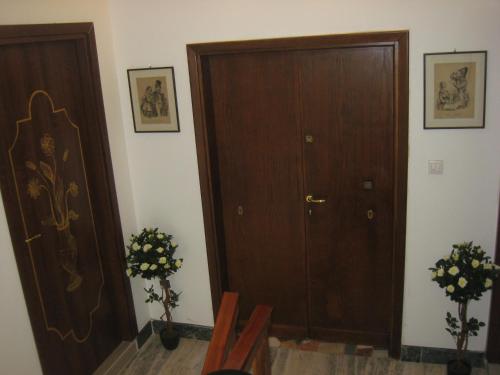 a hallway with a wooden door and two plants at Le Maschere in Mestre