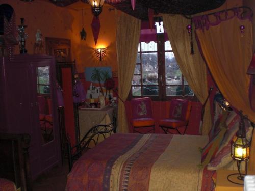 une chambre avec un lit et des chaises dans une pièce dans l'établissement Chambres d'hotes La Maison Bleue, à Souvans