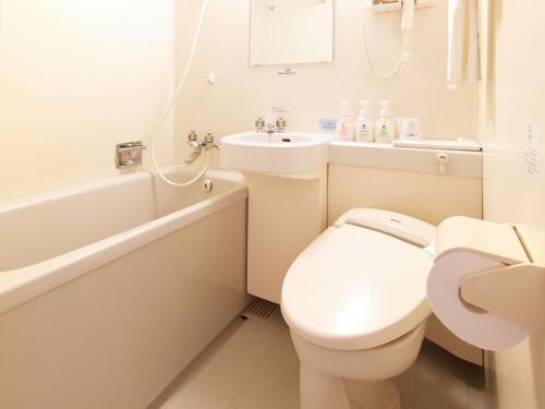 a white bathroom with a toilet and a sink at Hotel Roco Inn Okinawa in Naha
