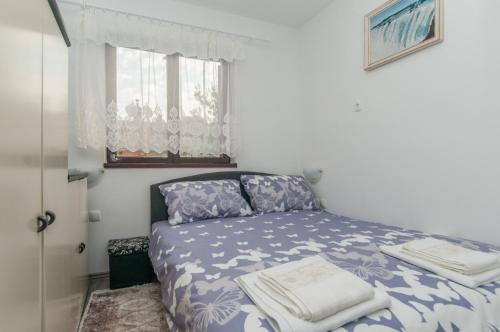 a bedroom with a bed with a blue and white bedspread at Zora Apartment in Mali Lošinj