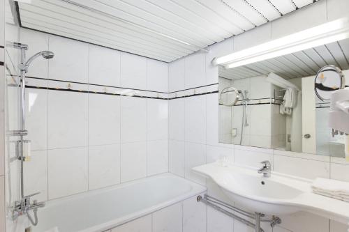 uma casa de banho branca com um lavatório e uma banheira em Montana Parkhotel Marl em Marl
