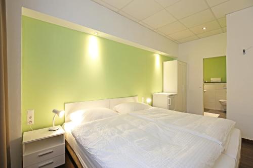 a bedroom with a white bed and a green wall at Business & City in Linz
