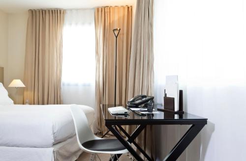 a hotel room with a bed and a desk with a phone at La Maison Champs Elysées in Paris