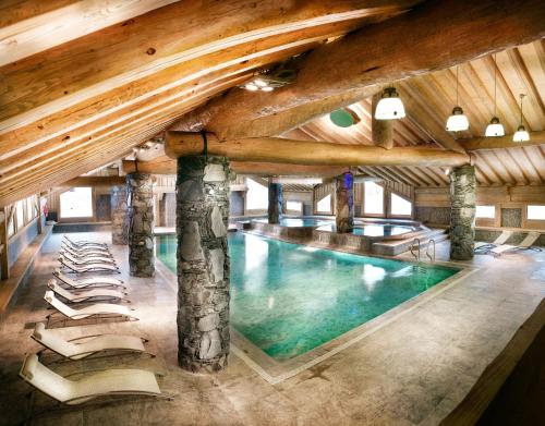 a large pool in a building with chairs around it at CGH Résidences & Spas Les Cimes Blanches in La Rosière