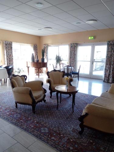 a waiting room with couches and tables and windows at Montra Odder Parkhotel in Odder
