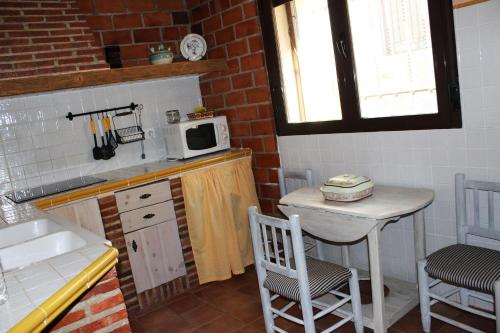 a small kitchen with a table and a microwave at Casa Rural El Quinto y Medio in Valdelacasa de Tajo
