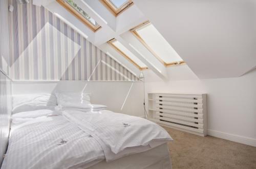 a attic bedroom with a white bed and skylights at Imperial Apartments - Nautica in Sopot