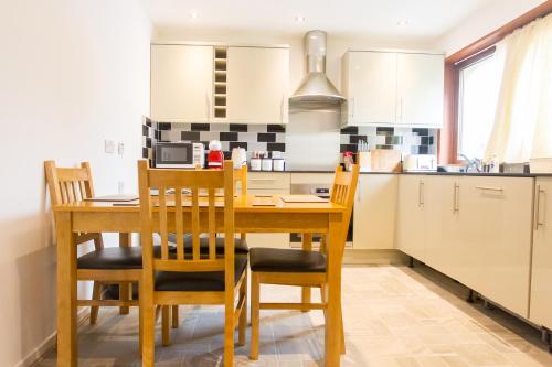 a kitchen with a wooden dining table and chairs at Coppice Cottage in Grantown on Spey
