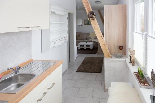 eine Küche mit weißen Schränken und einem Waschbecken in der Unterkunft Reiterhof an der Nordsee in Witzwort