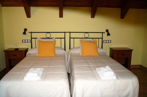 two beds with orange pillows in a room at Hostal Rural Casa Parda in Tramacastilla de Tena