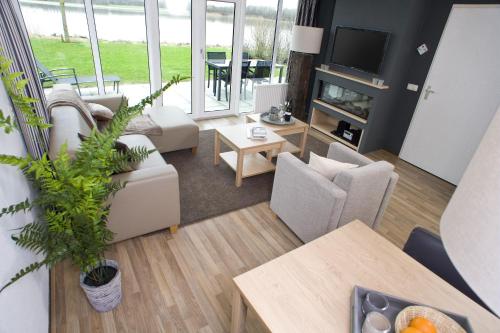 a living room with white furniture and a tv at Center Parcs Sandur Emmen in Emmen