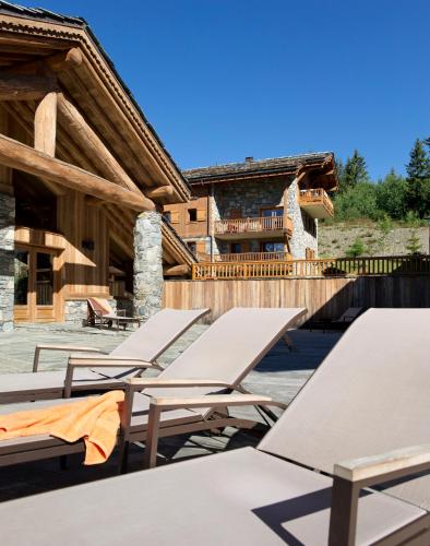 une rangée de tables et de chaises devant un bâtiment dans l'établissement CGH Résidences & Spas Les Cimes Blanches, à La Rosière