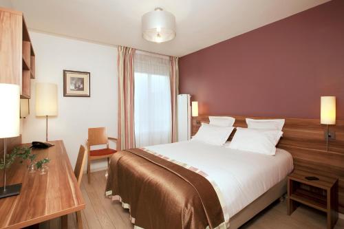 ビュール・シュリヴェットにあるレジドホーム ビュール ラ ガイヨネリーのベッドとデスクが備わるホテルルームです。