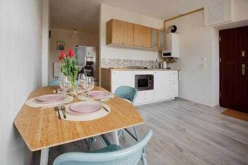 a kitchen with a wooden table with plates and chairs at Apartamenty Krakowskie 36 Lublin - Single Two in Lublin