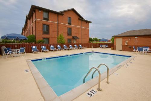 ein großer Pool mit Stühlen und ein Gebäude in der Unterkunft Extended Stay America Select Suites - Denver - Tech Center South in Centennial