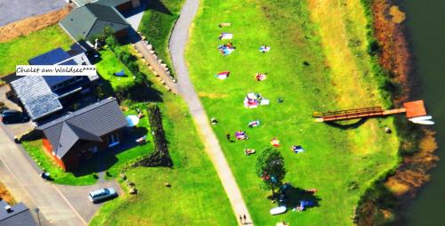 a group of people on a grassy field next to a house at Chalet am Waldsee direkt am Badesee Rieden mit Seeblick für bis zu 14 Personen Traumferienhaeuser-Eifel in Rieden