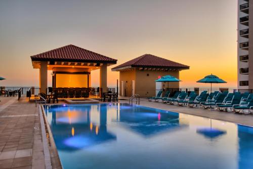 una piscina en un complejo con sillas y sombrillas en Edge Hotel Clearwater Beach, en Clearwater Beach