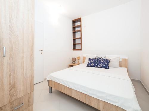 Schlafzimmer mit einem Bett mit weißer Bettwäsche und blauen Kissen in der Unterkunft Apartments Elena in Tivat