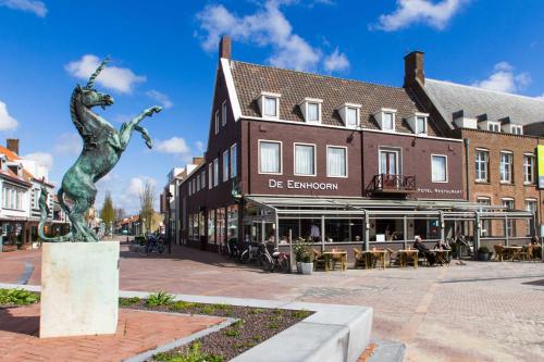 uma estátua no meio de uma rua com edifícios em De Eenhoorn em Oostburg