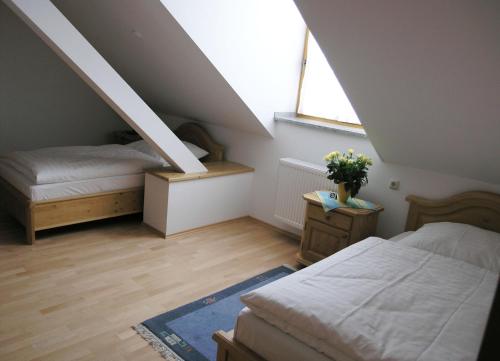 a attic bedroom with two beds and a window at Landgasthof und Hotel Forchhammer in Pliening