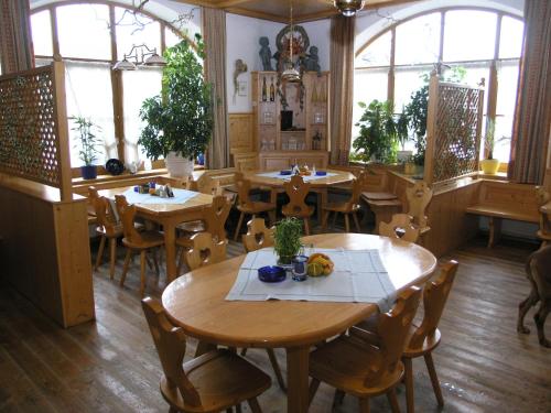 a restaurant with wooden tables and chairs and windows at Landgasthof und Hotel Forchhammer in Pliening