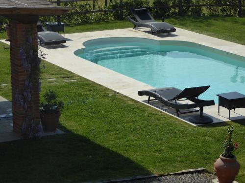 a swimming pool with two chairs and a table at Casa Vacanze Villa Cerine in Altopascio