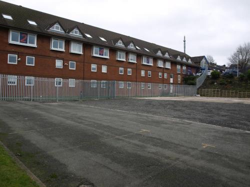 a large brick building with a fence next to a street at 247Hotel in Oldham
