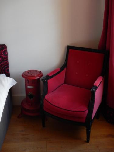 a red chair in a bedroom with a red stool at Le Clos de l'Abbaye in Cluny