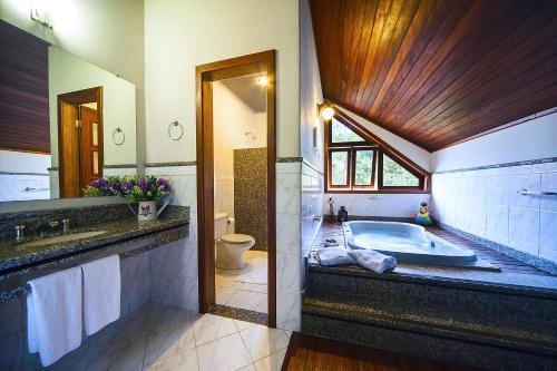 a bathroom with a tub and a toilet and a sink at Pousada dos Pinhos in Pedra Azul