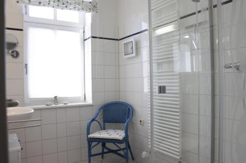 - une chaise bleue dans la salle de bains pourvue d'une douche dans l'établissement Villa Concordia Apartment Hiddensee, à Binz