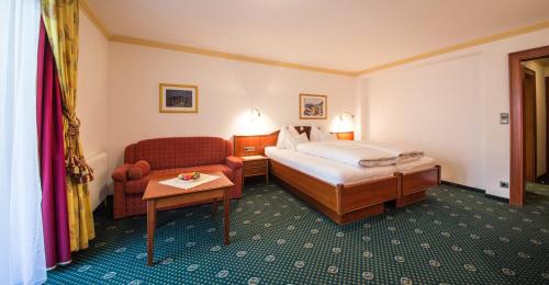 a hotel room with a bed and a chair at Hotel Kristall in Sankt Anton am Arlberg