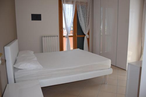 un letto bianco in una stanza con finestra di Milano Dune Family Apartment a Lido di Jesolo